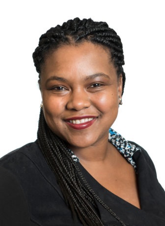 Kisha Bird headshot (in library) alt text: racial and ethnic bias: smiling woman with long braids, black jacket, print blouse