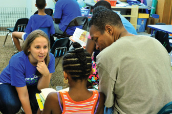 A teacher helps a family practice how to ask questions while reading at the Springboard Collaborative summer program at Wissahickon Charter School in Philadelphia.