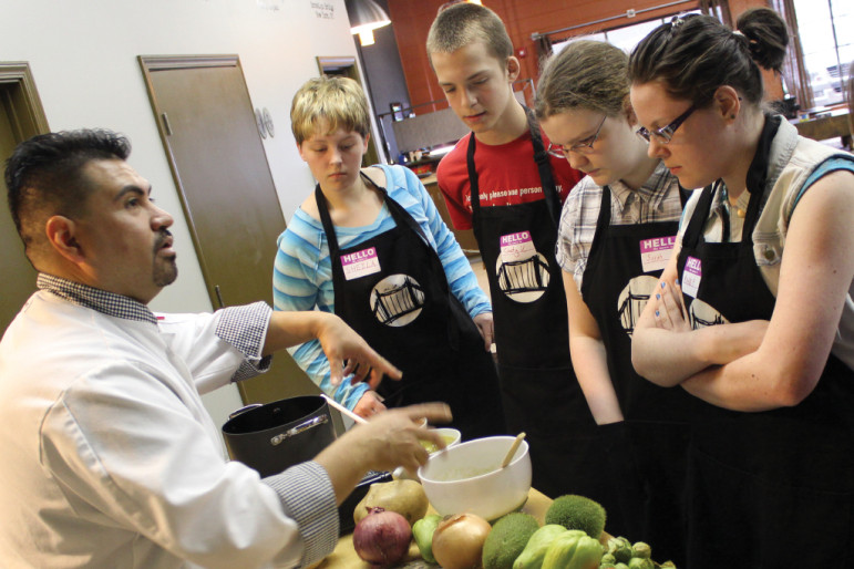Chef Gus with Azteca Foods leads a hands-on culinary arts demonstration with teens from The Bridge.