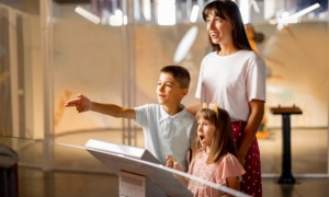 Museum project support grants: mom and children looking at museum exhibit excitedly