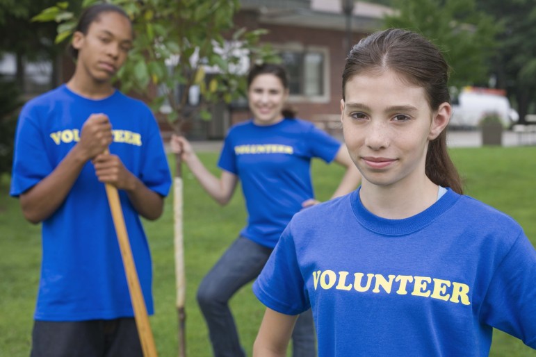 Program Quality and Youth Leadership: Three teens standing with garden tools in blue t-shirts with text :volunteer".