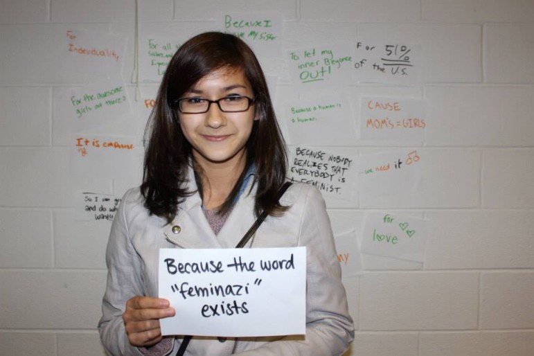 Maddy Goh holds a sign answering the question: Why do we need Day of the Girl?