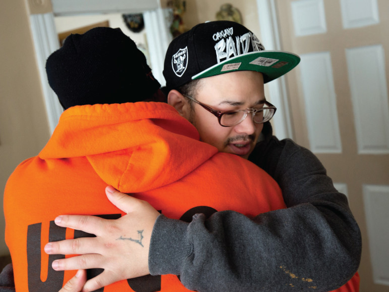UTEC street worker Johnny Chheng (left) hugs Miguel Vasquez at Vasquez’s home in Lowell, Massachusetts. Vasquez participates in mentorship with UTEC’s street team.