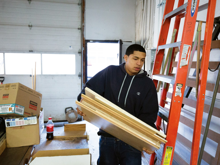 Franklin Diaz moves planks of wood into the under-construction woodworking shop at UTEC headquarters. 