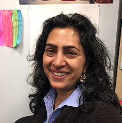 Sharmeela Mediratta: Headshot smiling woman with long dark curly hair wearing light-colored shirtand dark jacket