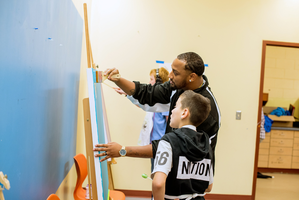 At Boys & Girls Club of Greater Milwaukee, artist Vedale Hill on right shows boy how to paint mural.