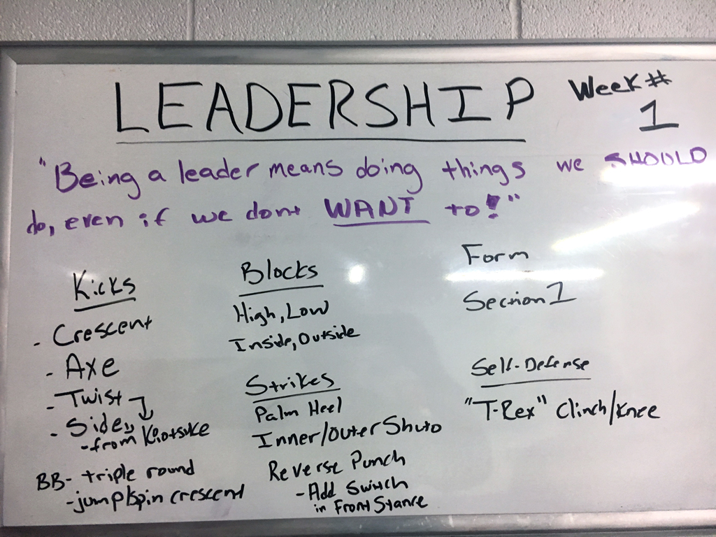 Whiteboard is covered with leadership quote and martial arts information.