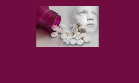 Pill bottle tipped over and spilling out pills next to young child's face.