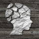 Paper cutout of child's headwith severalcracks in skull on wood background