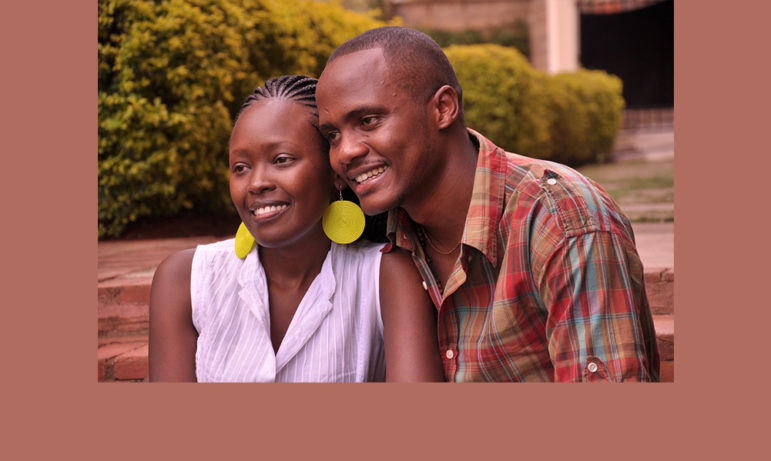 Foster Parents: Black couple sit close smiling inot camera