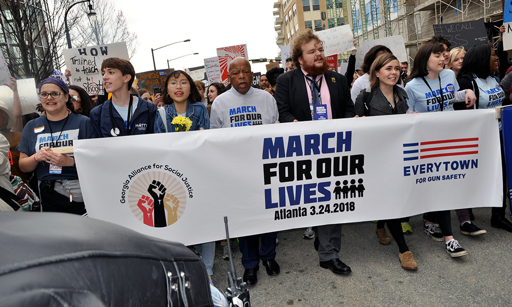 Georgia Rep. John Lewis, in a March for Our Lives T-shirt, is part of group carrying a banner.