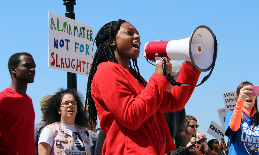 March for Our Lives: Student leader Monique Sampson of the University of North Florida, wearing a red jacket, speaks into a megaphone.
