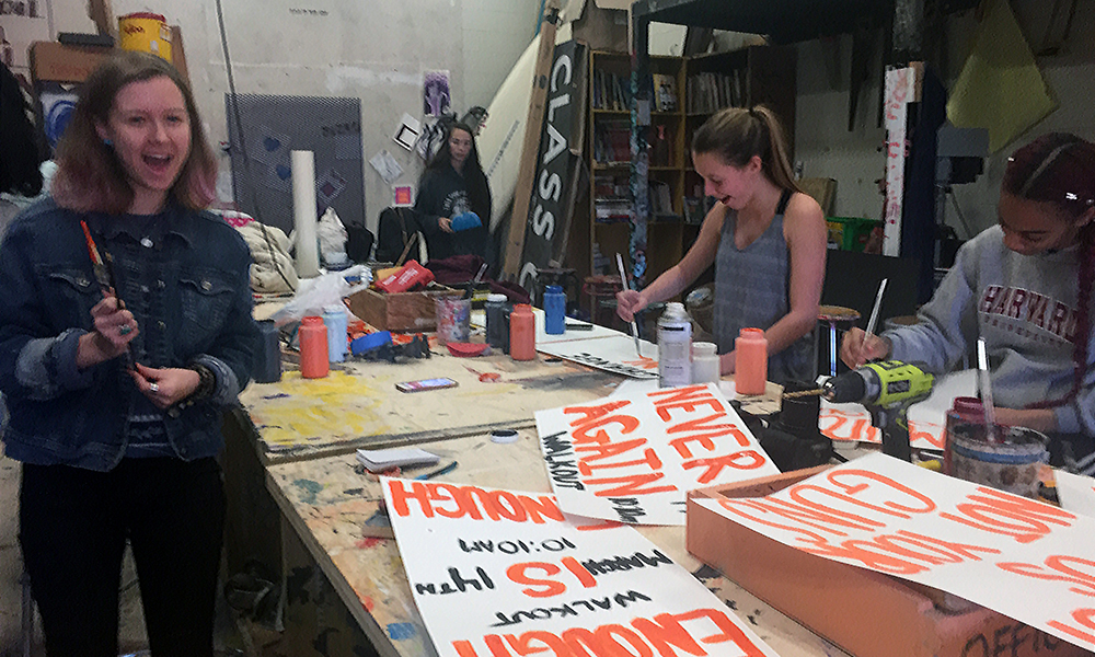 Walkout: 4 casually dressed female high school students paint posters.