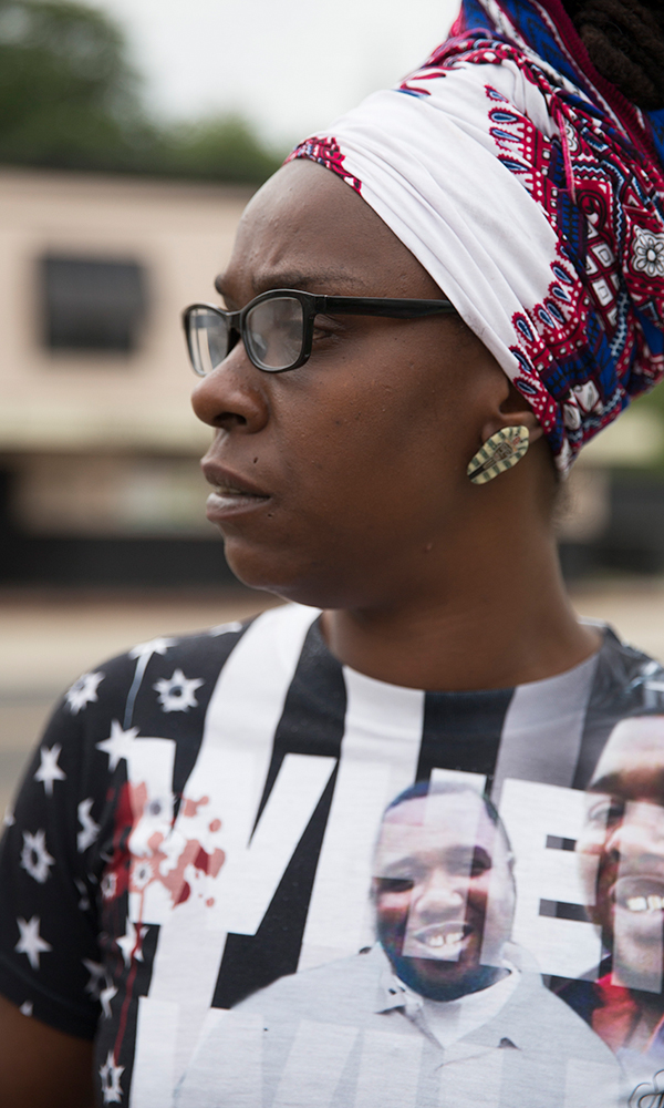 Side profile of woman with glasses, earrings, multicolored head wrap and multicolored top.