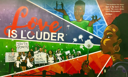 Gun control: Colorful mural shows positive slogans, young man holding up tiny people on his hands, young woman blowing the seeds off a puffball.
