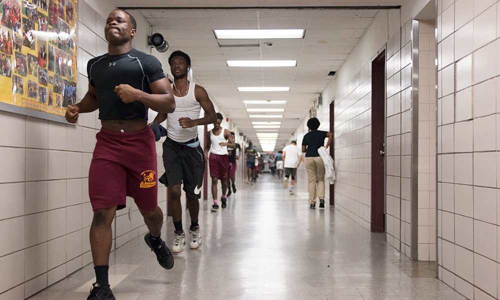 young football players jogging through hallway