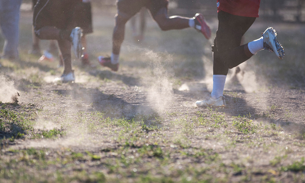 football players running with dust rising below their feet