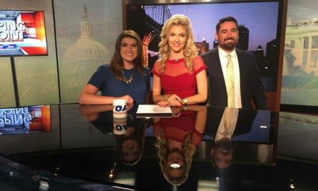 Conservatives: 3 people on TV set: smiling young woman in blue dress, necklace, medium-length brown hair; smiling blonde woman in partly see-through red dress; smiling young man with dark beard, mustache, suit, white shirt, striped yellow tie.