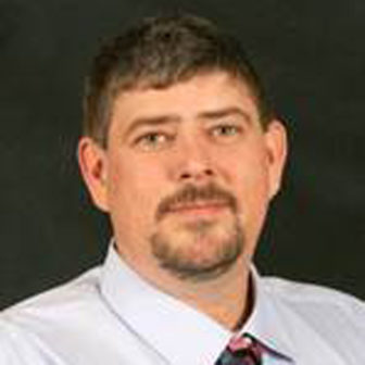 Foster care: Brandon Nichols (headshot), chief deputy director of Department of Children and Family Services, serious-looking man with beard, mustache wearing white shirt, patterned tie.