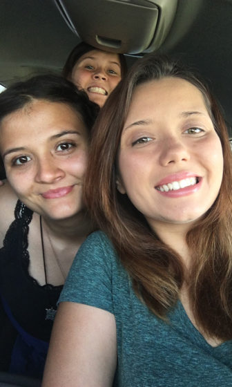 Foster care: 3 smiling young woman in car crammed together in selfie.
