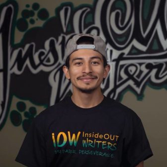 InsideOUT Writers: Jimmy Recinos (headshot), InsideOUT Writers editor, instructor, community advocate, smiling young man with mustache in backwards gray ball cap, black T-shirt labelled IOW InsideOUT Writers.