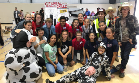 STEM: Students in gym cluster in front of their project. Two are dressed as cows.