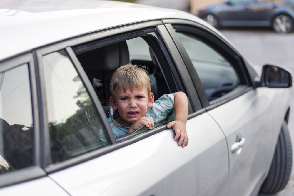 Foster care: child separated from one parent leaving in a car, sad and crying