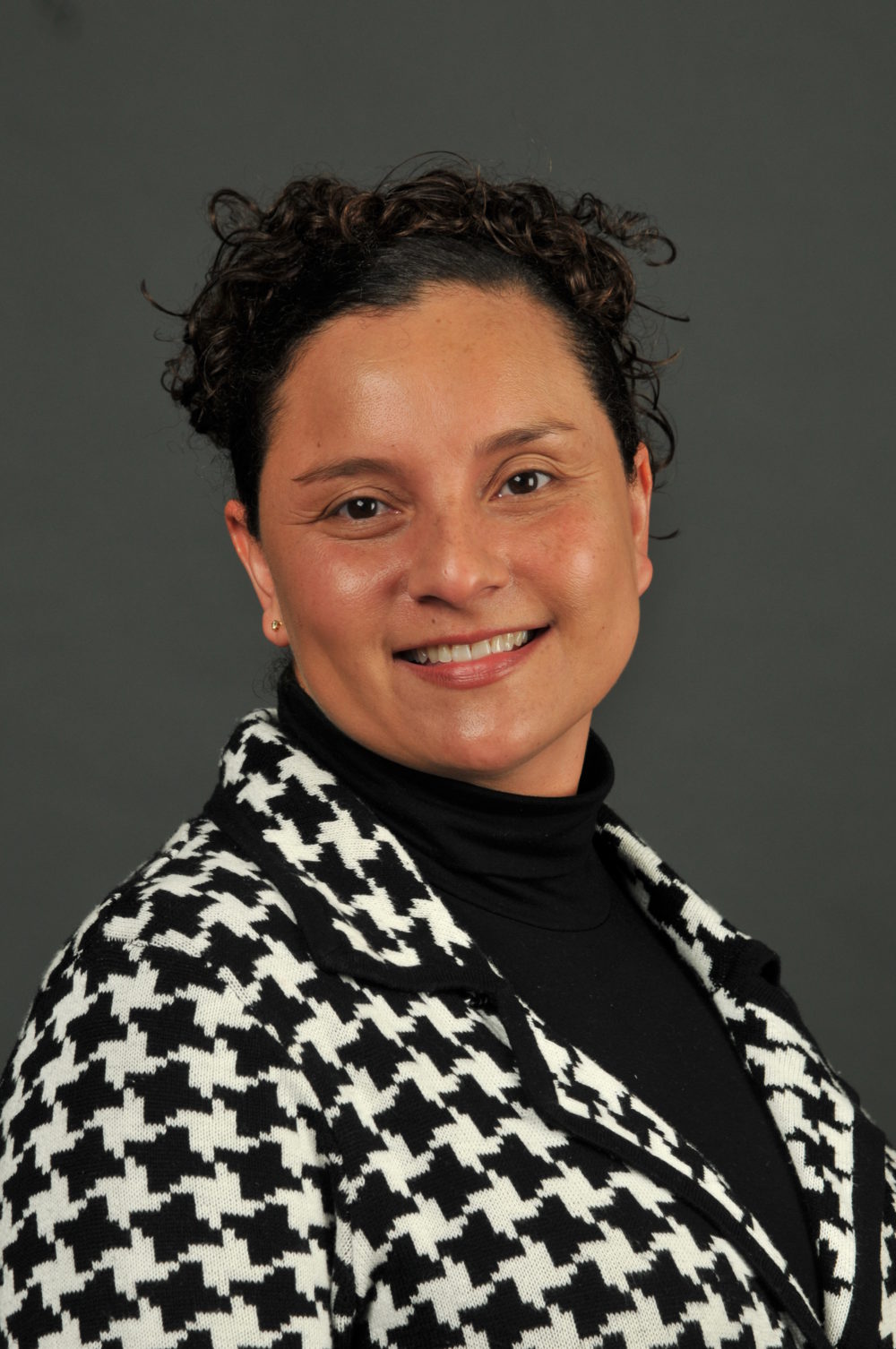 Unhelpful Social Narrative: Marcy Peake (headshot), director of diversity and community outreach initiatives in the College of Education and Human Development at Western Michigan University, smiling woman with houndstooth jacket, black top. 