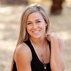 eating disorder: Sammie Marie (headshot), occupational therapy student, smiling young woman with long blonde hair kneeling on ground near trees wearing denim shorts, blank tank top, boots.