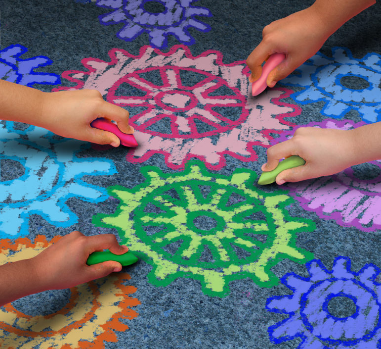 Colorful chalk drawing of meshing cogs being drawn by children on sidewalk.