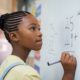 inner city education grants, young black female student doing math on white board