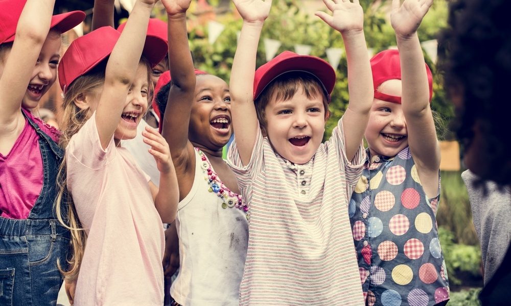 youth summer learning grants: happy children raising hands outside