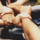 collaboration: People grip each other’s wrists.