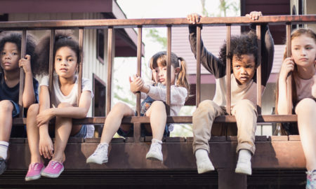 child welfare: Multicultural little children sitting behind fence.