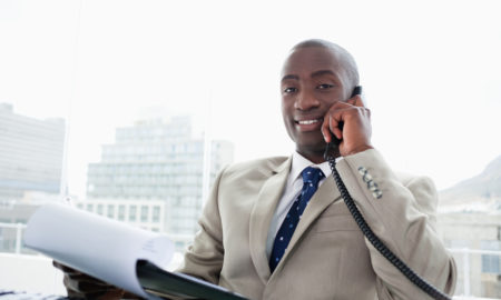 fundraising: Smiling businessman on the phone while reading a document in his office