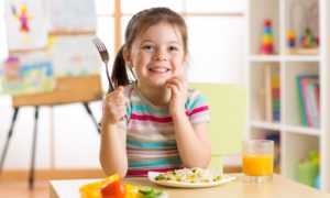 food access, child health report, young girl happy at table holding fork