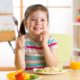food access, child health report, young girl happy at table holding fork