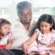 kinship care: Asian grandparent and grandchildren reading story book.