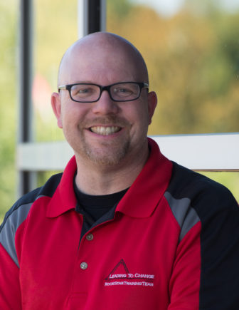 youth philanthropy: Eric Rowles (headshot), president of Leading to Change, smiling bald man with beard, mustache, dark glasses wearing red, gray and black top