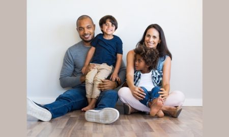 Grant: Mom , Dad & 2 young sons seated on wood floor against white wall
