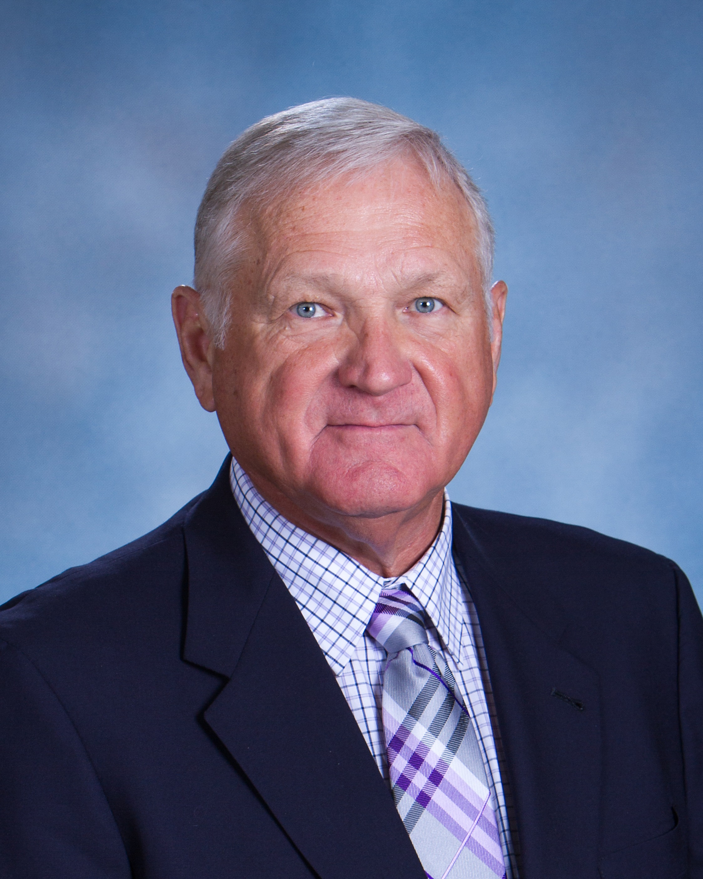 Transgender: Jim Tenopir (headshot), executive director of Nebraska School Activities Association, serious-looking man with gray hair, dark jacket, checked shirt, striped tie.