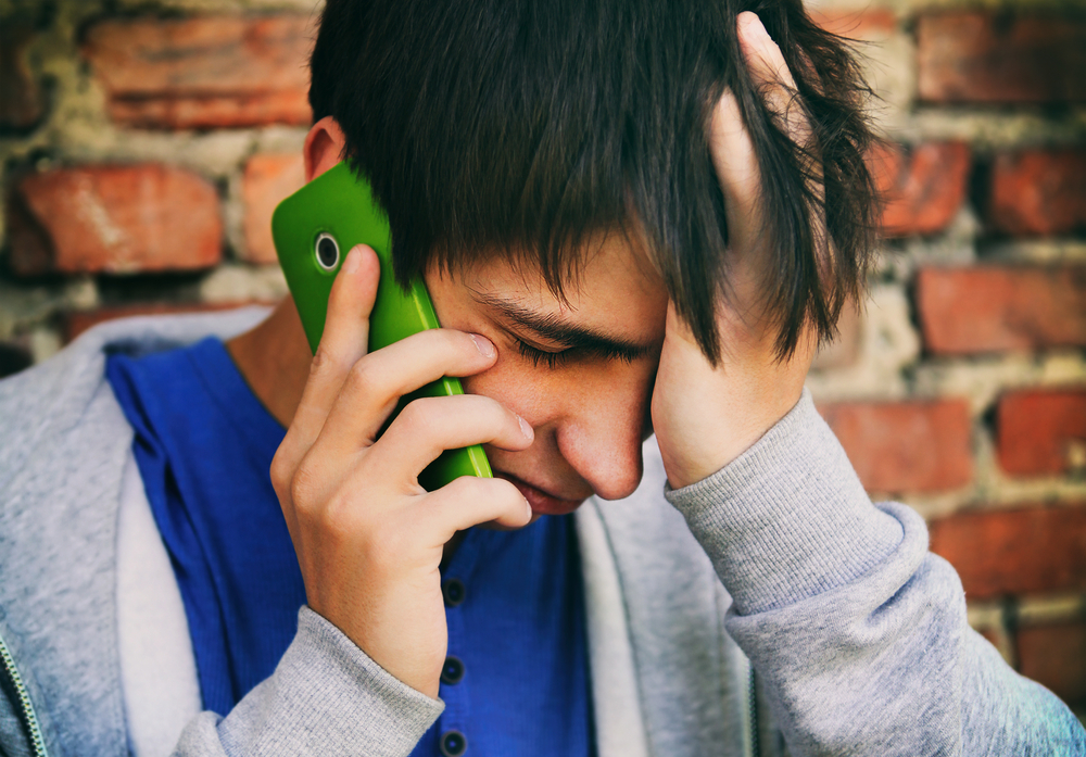 youth peer lines: Sad Young Man with Cellphone on the Brick Wall Background