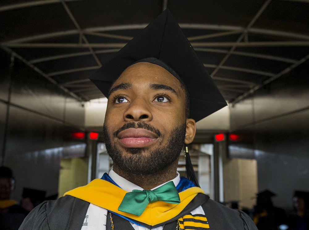 youth violence: Soulful-looking young man in graduation gown, mortarboard with beard and mustache looks off to left