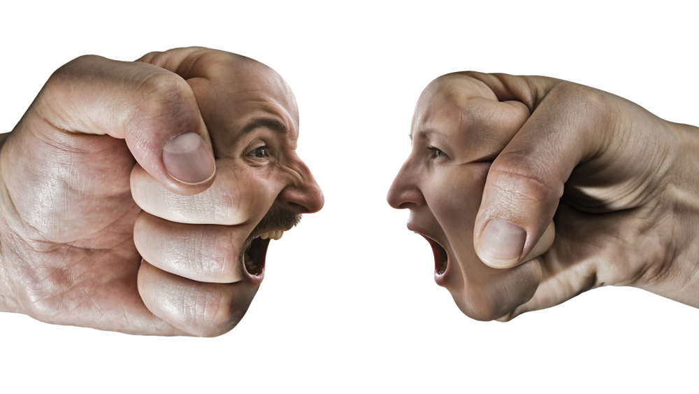 TAG: Two fists with a male and female face collide with each other on isolated, white background.