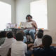 afterschool: Woman reads picture book to children sitting on the floor.