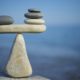 OST: Balance of stones. To weigh pros and cons. Balancing stones on the top of boulder. Close up. Balance of stones on a blue sky background with a copy space. Scales. Stones balance, sustainability.