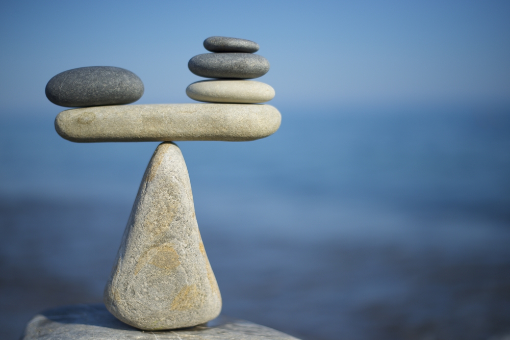 OST: Balance of stones. To weigh pros and cons. Balancing stones on the top of boulder. Close up. Balance of stones on a blue sky background with a copy space. Scales. Stones balance, sustainability.