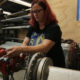 foster care: Woman with red hair, glasses, T-shirt works with machinery.