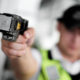 Tasers: Closeup view of a loaded stun gun in a hand of a young man wearing high visibility vest