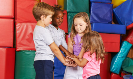 SEL: 4 children stacking their hands in kindergarten gym